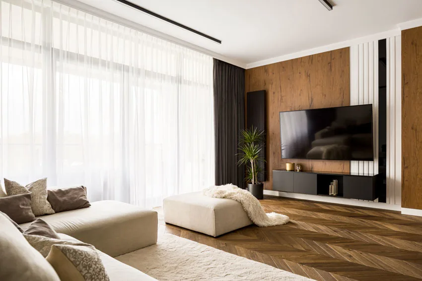 Room with wood accents, sheer curtains and white ottoman