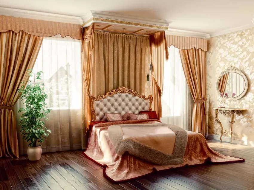 Luxurious bedroom with silk curtain, wood floor, bedspread, headboard, pillows, vanity table, mirror, and indoor table