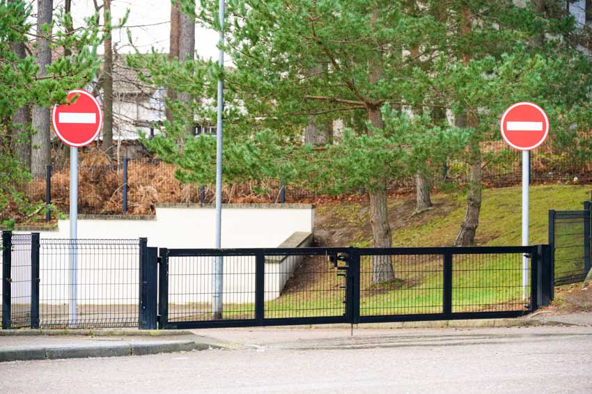 Manual swing barrier gate connected to a metal fence