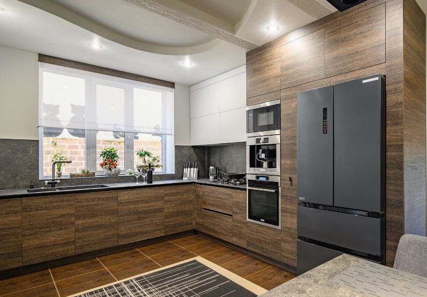 A modern kitchen with decorative veneers plywood cabinets, black countertops and new appliances