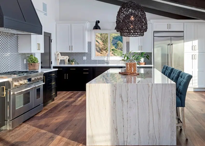 Modern kitchen with waterfall island, black and white accents and wall sconce lighting 
