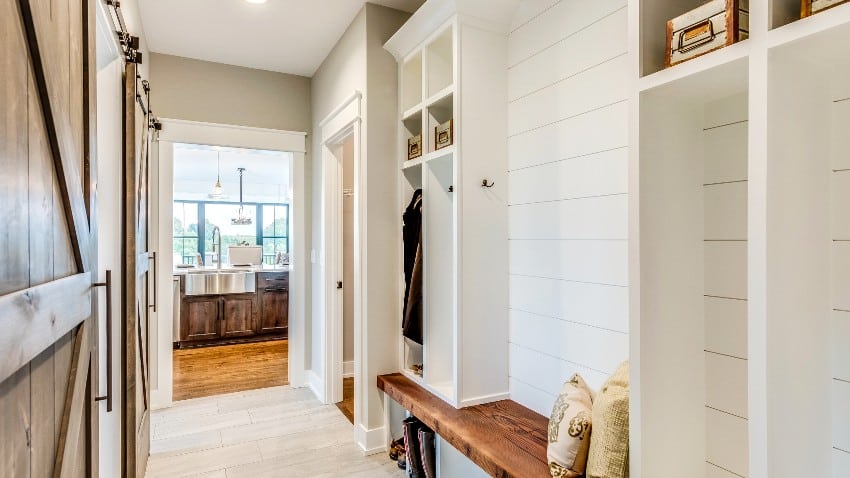 Mudroom with white horizontal shiplap walls, tile floors and natural wood bench with pillow