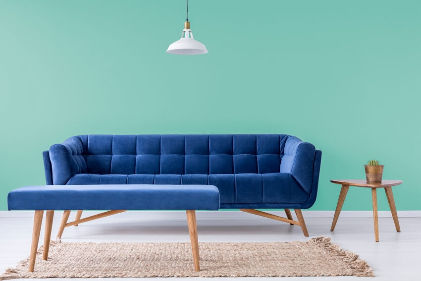 Navy blue comfy couch and table with cactus in turquoise wall room