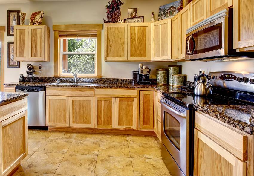 Nicely decorated kitchen room interior with hickory kitchen cabinets, tile floor, granite counter tops and built in steel appliances