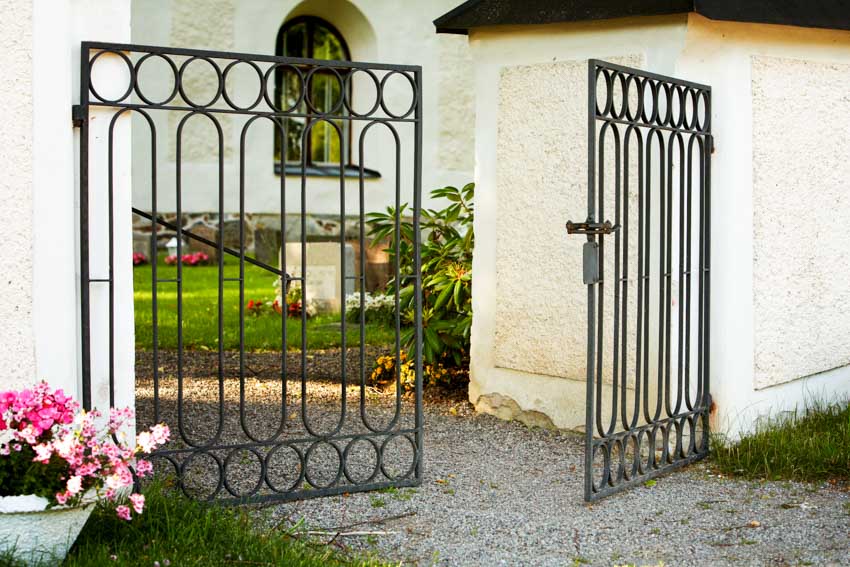 Outdoor area with metal swing gate, garden, and wall