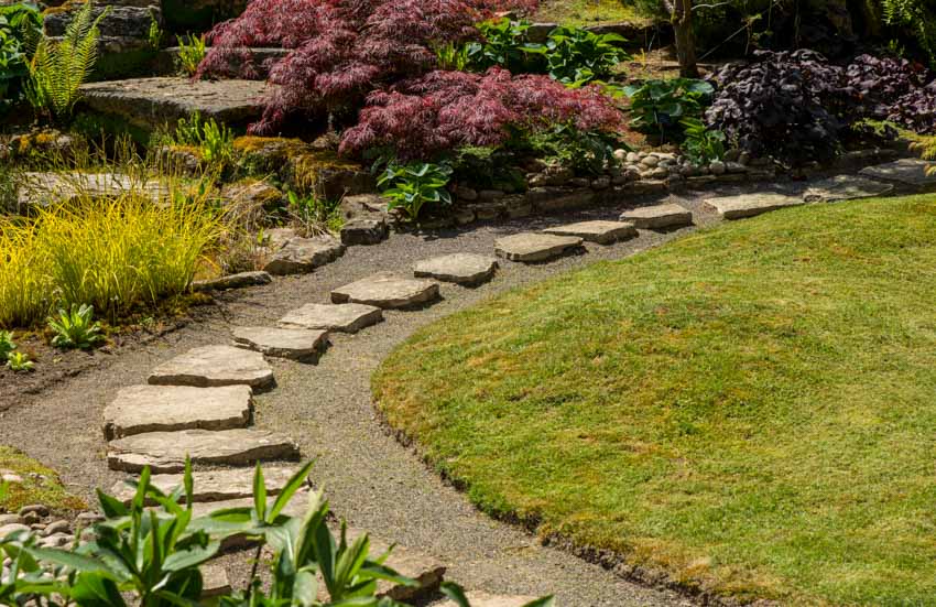 Outdoor garden with landscaping flagstone rocks for a walkway, hedge plants, and flowers