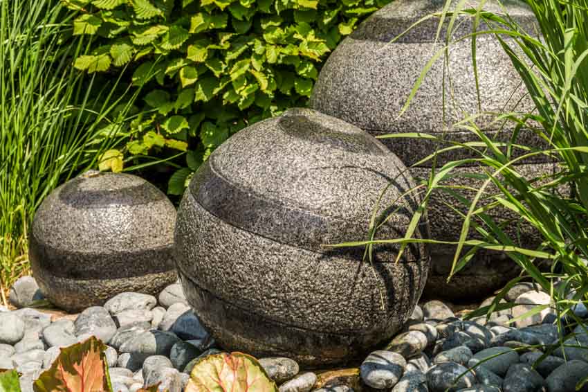 Outdoor garden with sphere fountain, landscaping rocks, and plants