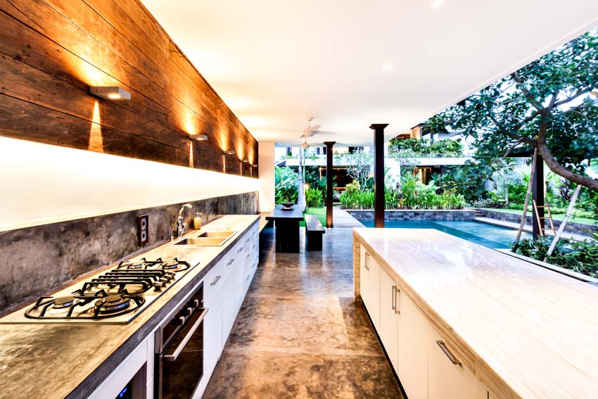 Outdoor kitchen with epoxy countertop, island, stove, and wall mounted lighting fixtures