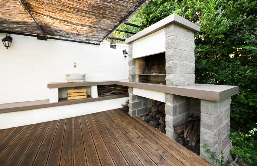 Outdoor kitchen with natural stone, wood floor, countertop, fireplace, and sink