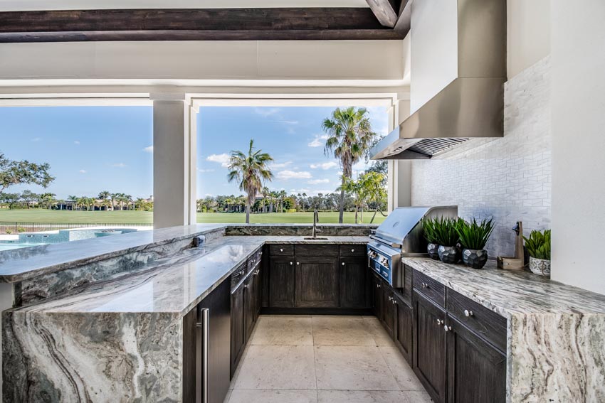 Outdoor kitchen with range hood, epoxy countertop, cabinets, and stove