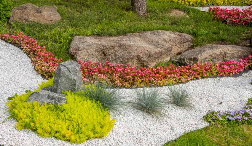 Outdoor lawn area with marble landscaping rocks, plants, and flowers