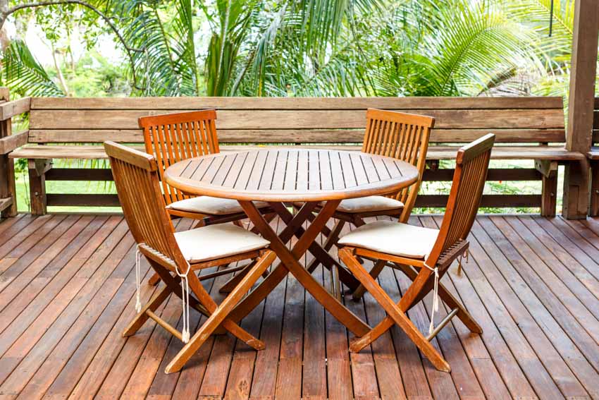 Outdoor patio with teak wood, table, chairs, and wooden plank flooring
