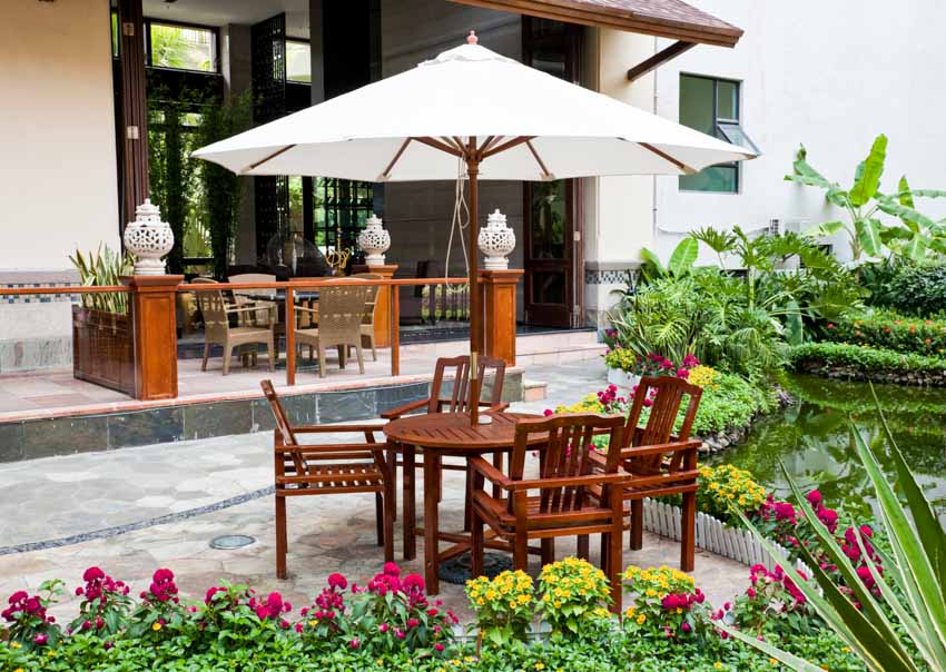 Outdoor patio with umbrella shade, table, chairs, plants, and flowers