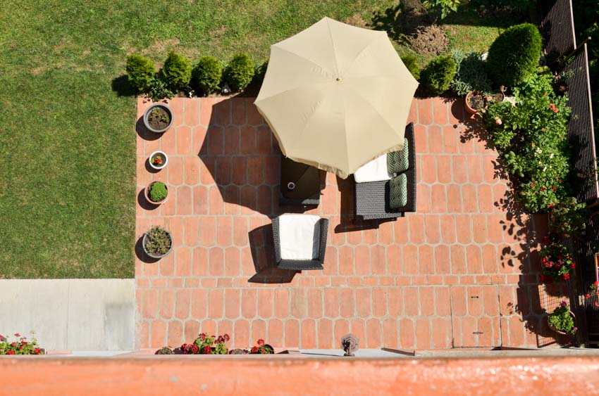 Patio with brick surface, plants, and umbrella shade