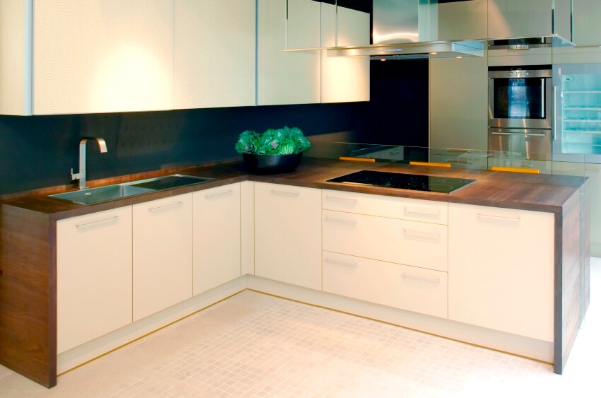 A simple kitchen interior with linoleum countertop, cabinets, drawers, cooktop and oven