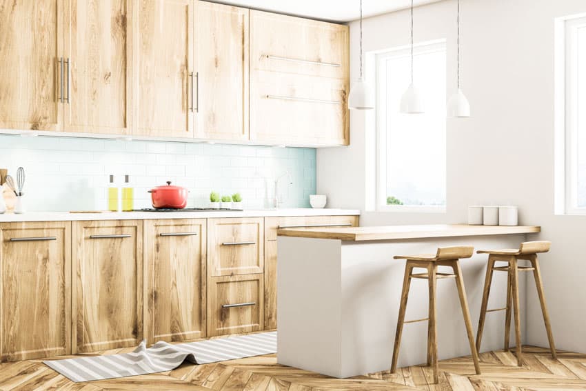 Simple kitchen with island, wood chairs, countertop, tile backsplash, cabinets made from hickory, and window