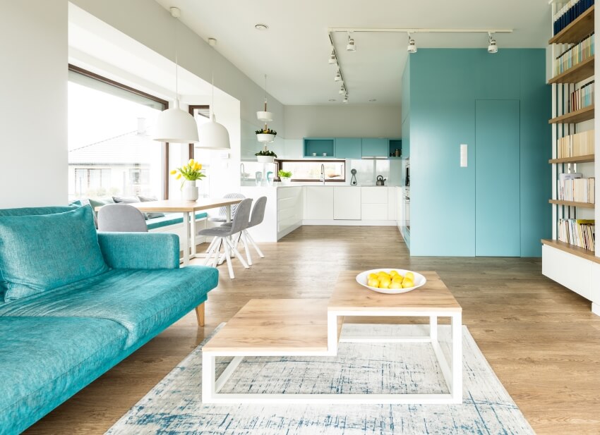 Spacious apartment interior with some colors that go with turquoise including wooden table, white walls and other furniture with kitchen in the background