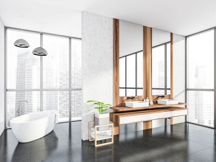 Spacious bathroom with oversized tiles, floating vanity wood countertop, sink, mirror, tub, and windows