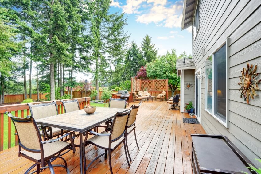 Spacious oil stained backyard wooden deck with patio area, outdoor furniture and attached pergola
