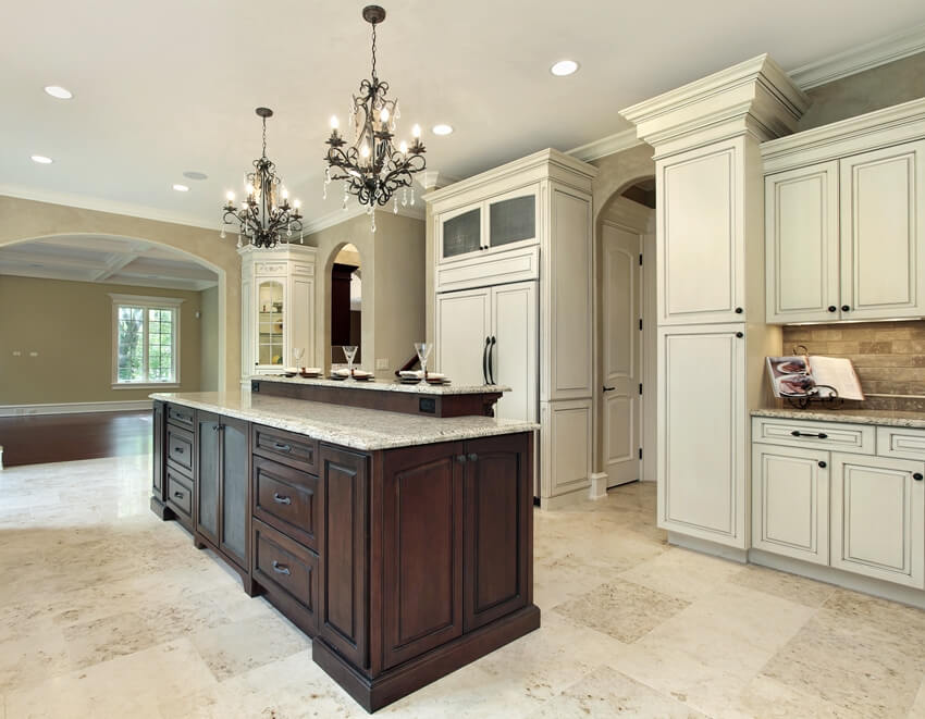 Traditional kitchen interior with chandeliers, hardwood island with granite countertops, white cabinets and large format terrazzo tiles