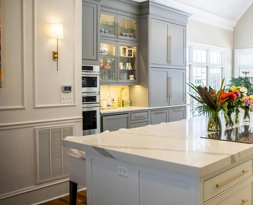 Traditional kitchen with two toned cabinets, marble island counter and wall sconce