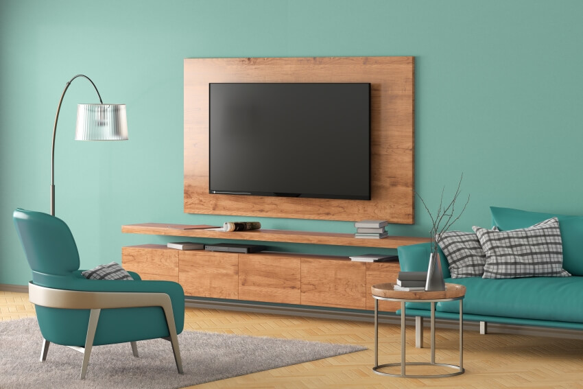 TV on the turquoise wall of modern living room with cabinet, and cyan leather armchair couch