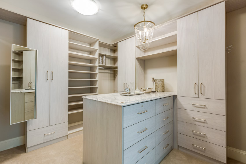 Walk in closet with island, organizer shelves, cabinets, drawers, and ceiling lights