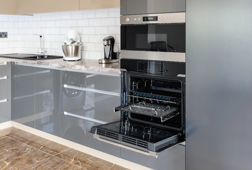 Kitchen with wall types of ovens, white backsplash, slab panel cabinets