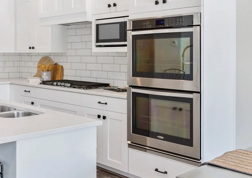 White kitchen with oven and microwave beside it 