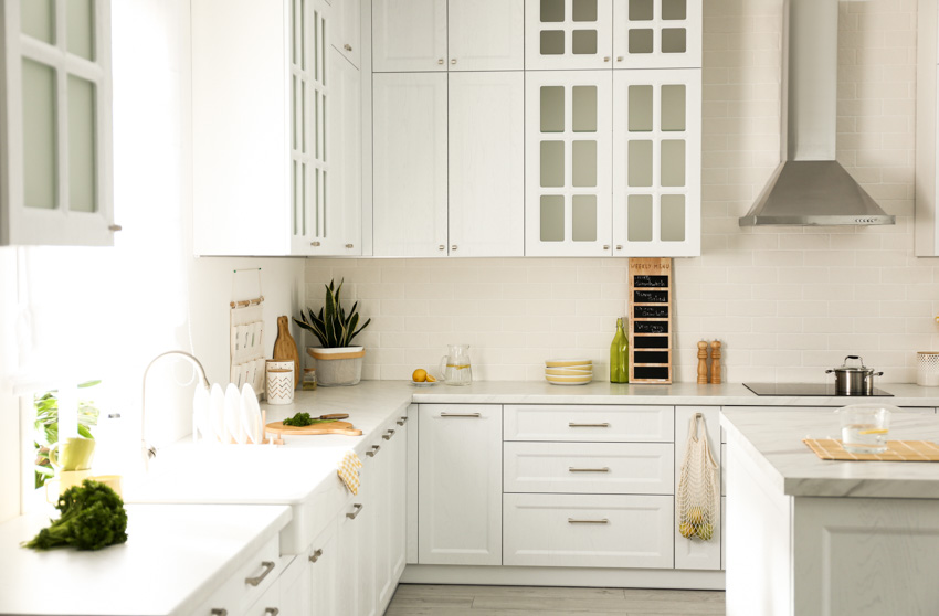 White kitchen with countertop, backsplash, window, and cabinets