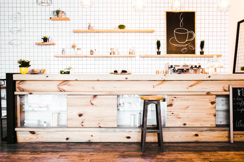 Wood coffee bar with countertop, floating shelves, tile wall, high stool, and wooden floors