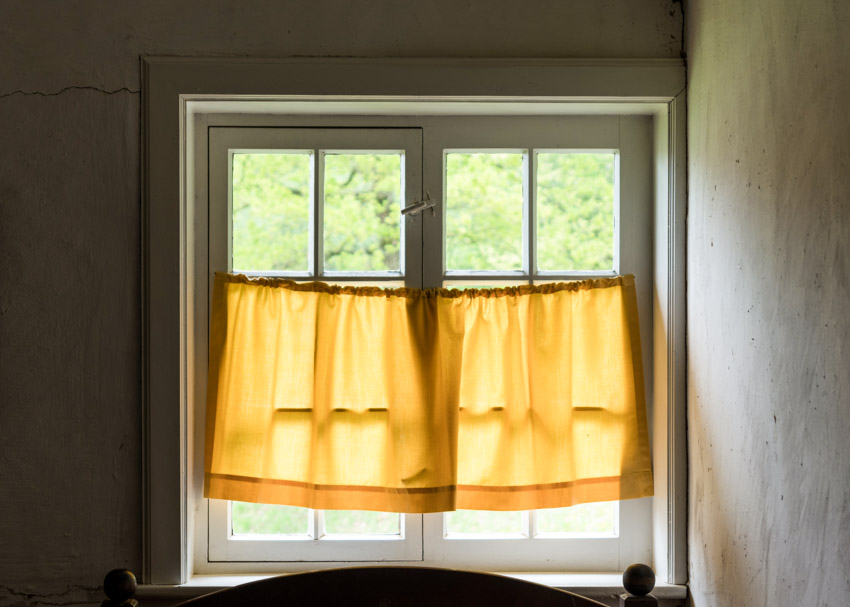 Yellow tier curtain on a white casement window