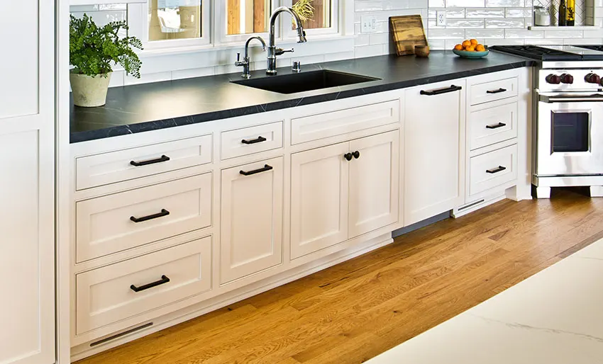 Clean minimalist kitchen with white inset cabinets black granite countertop wooden floor