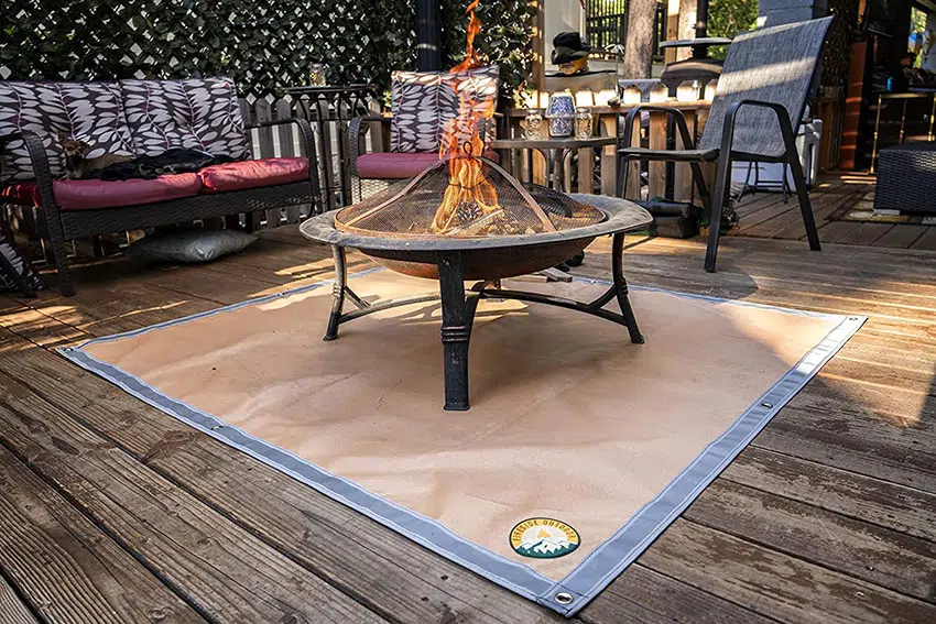 a round steel fire pit on a fire pit pad placed on a wooden deck