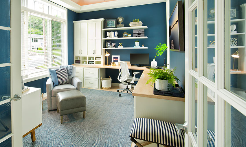 Home desk with blue paint floating shelves armchair and ottoman indoor decorative plants window blinds