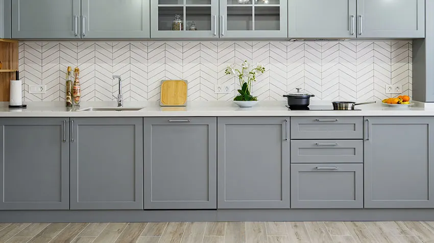 Kitchen with gray overlay cabinets herringbone backsplash