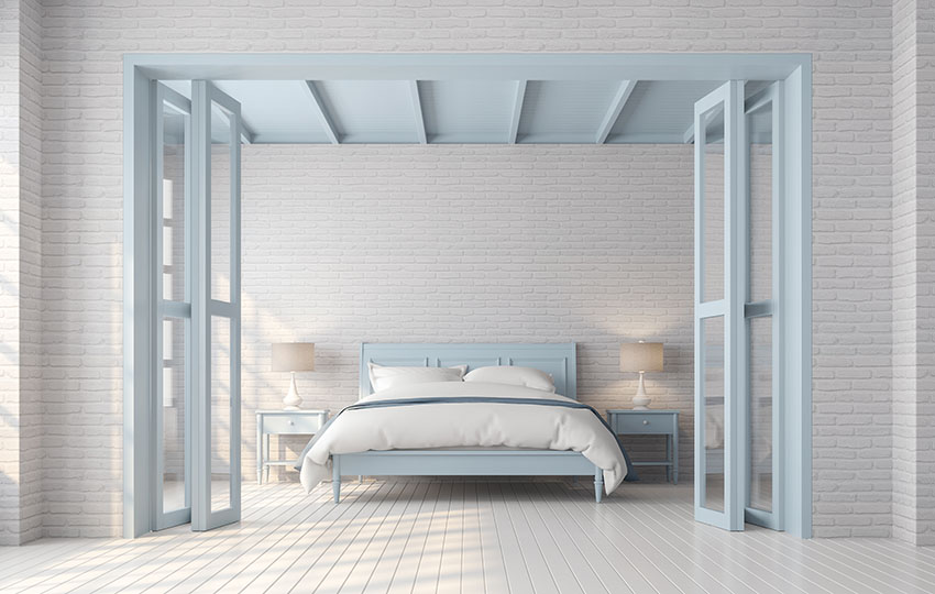 Large bedroom with bifold doors white floor white brick walls platform bed bedside table