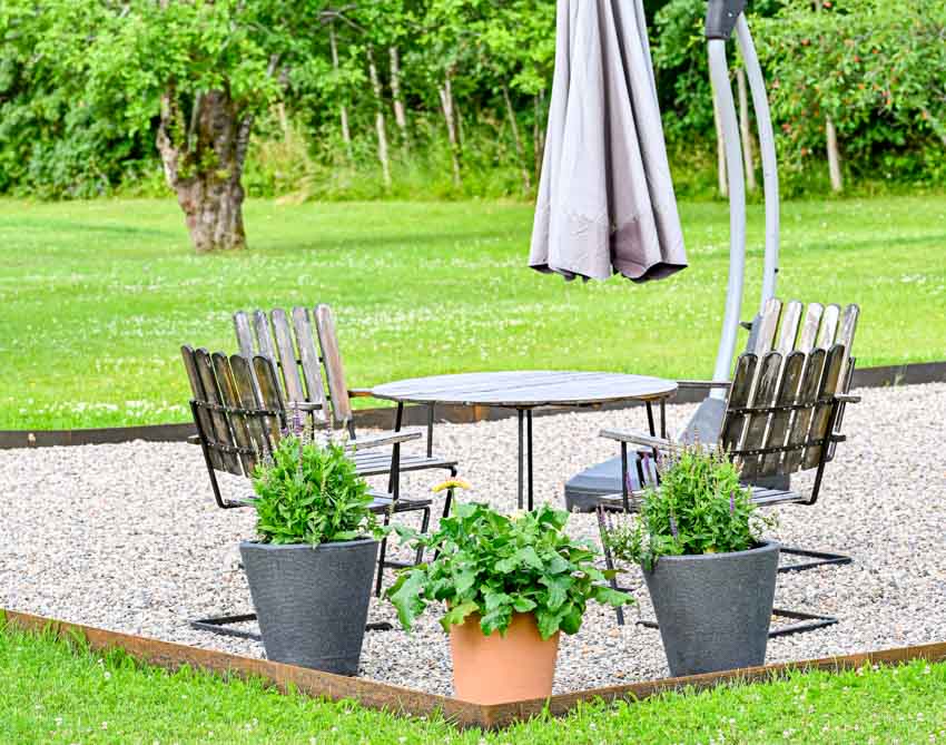 Backyard with crushed granite, chairs, table, and potted plants