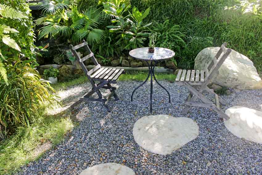 Backyard with decomposed granite patio, table, chairs, plants, and large stones