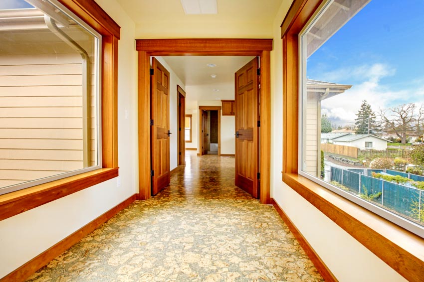 Bare hallway with wood framed glass windows, cork flooring, and doors