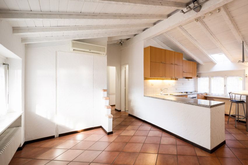 Bare kitchen with vaulted ceiling and terracotta tile floor