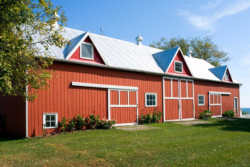 Barn exterior with metal board and batten siding, dormers, barn doors, and windows