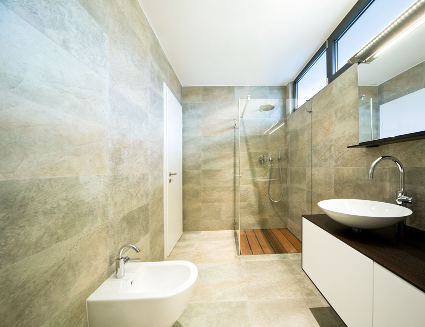 Bathroom with granite shower, toilet, sink, countertop, mirror, and window