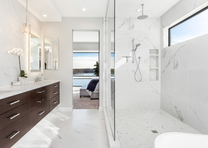 Bathroom with porcelain shower wall, glass divider, drawers, countertop, mirror, and window 