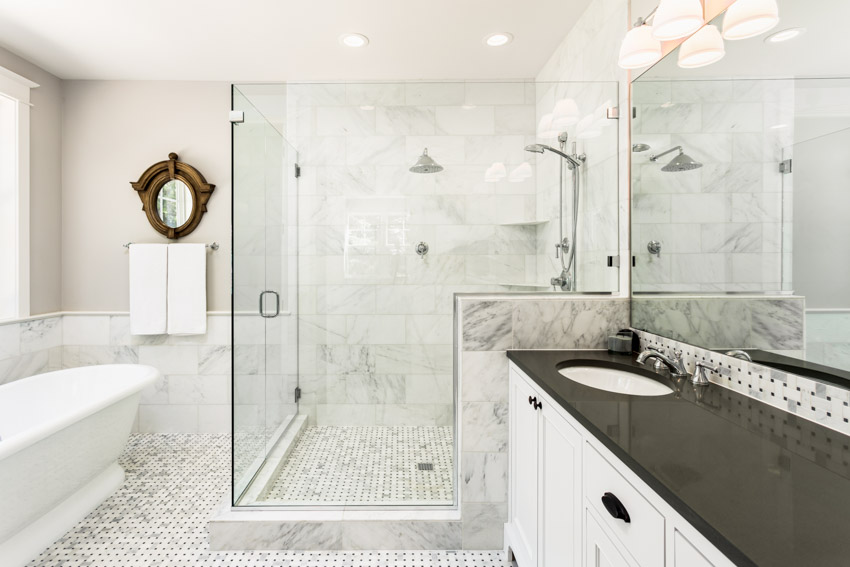 Bathroom with shower walls, glass enclosure, countertop, sink, mirror, and tub