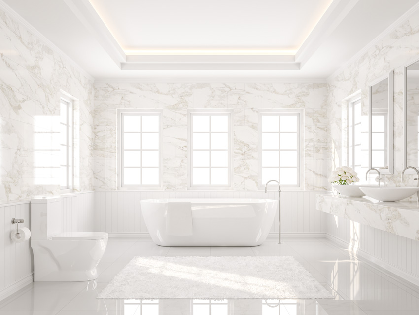 Bathroom with tub, high gloss tiles, toilet, vanity area, mirror, and windows