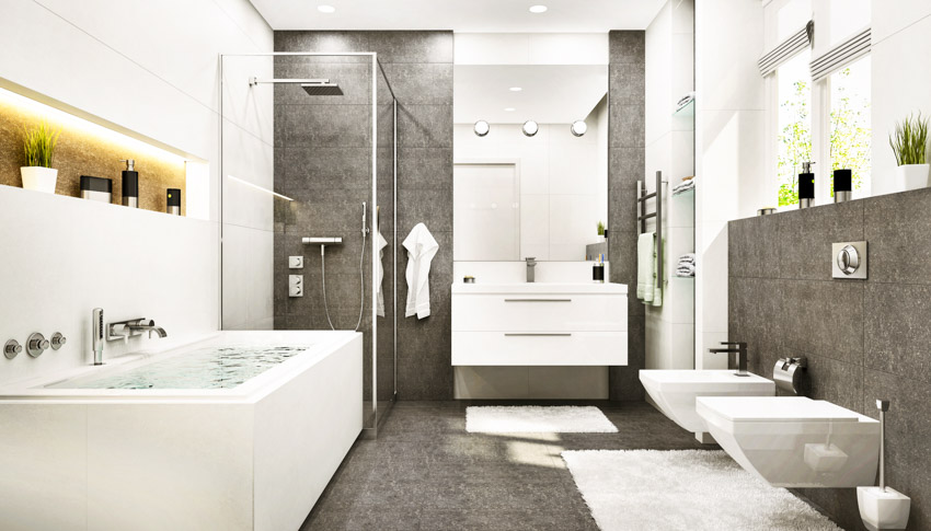 Bathroom with tub, toilet, bidet, mirror, floating countertop, granite shower wall, and glass divider