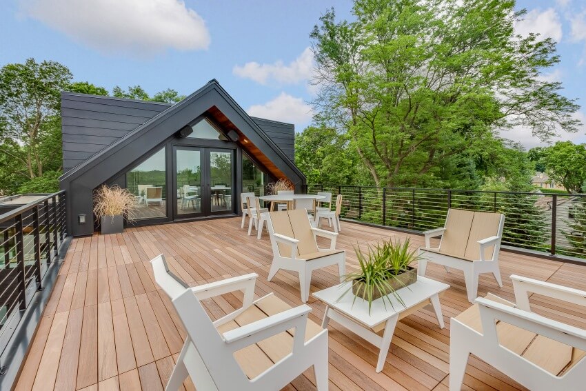 A beautiful home with Douglas fir deck furnished with wooden tables and chairs on a sunny day