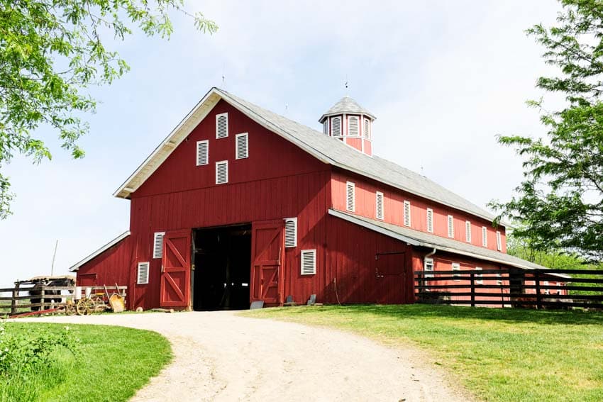 Beautiful red and white barn with doors, windows, shade, and pitched roof