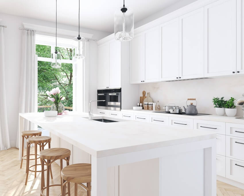 Kitchen with pendant lights, wooden stools, white island and cabinets